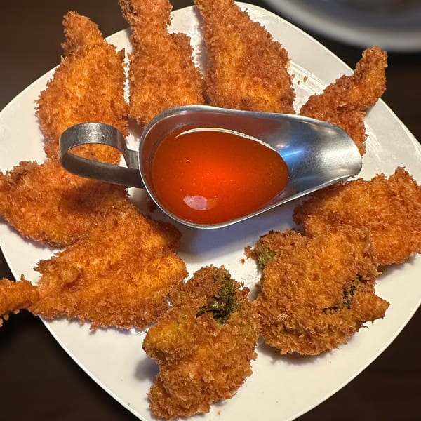 Plate of assorted golden-brown breaded appetizers arranged around a serving dish of red dipping sauce.