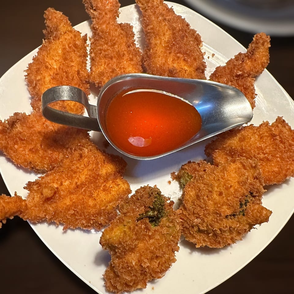 Plate of assorted golden-brown breaded appetizers arranged around a serving dish of red dipping sauce.